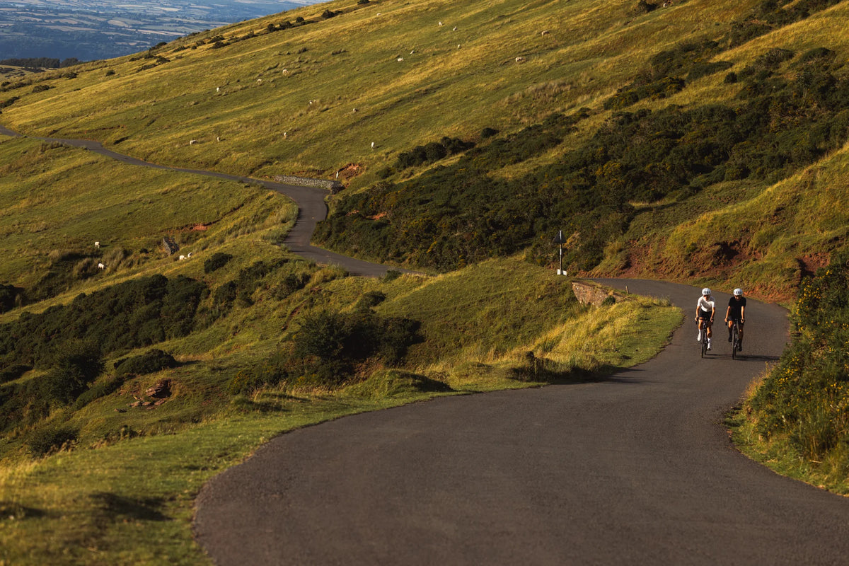 Two riders on Pearson Forge bikes climbing a switchback road in the Brecon Beacons