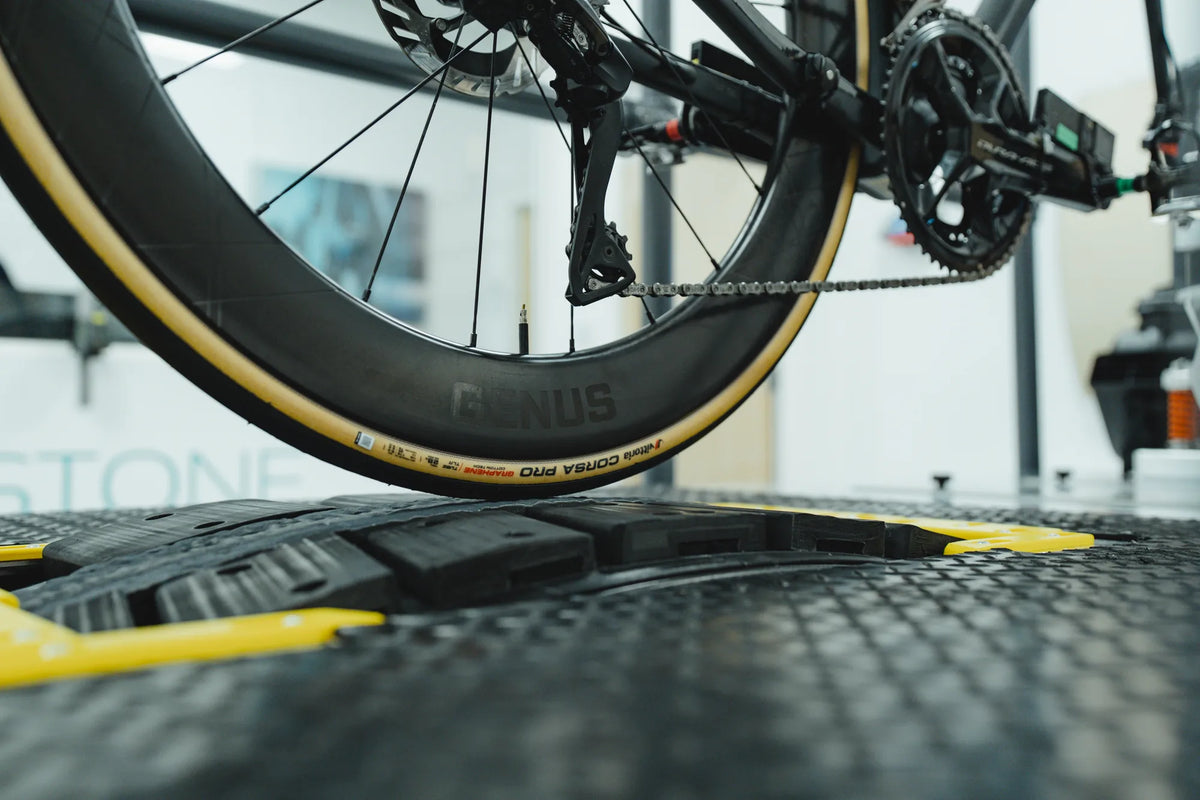 Close up of the rear tyre pressed into the weighted roller of the pedal rig